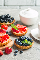 Fresh homemade berrie tarts with blueberries, blackberry and strawberries on gray background