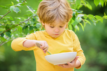 son and eating milk porridge. cereal for breakfast. good morning. small boy eating outdoor. Child development. Little boy eat healthy food. childhood happiness. healthy food and dieting. Family day