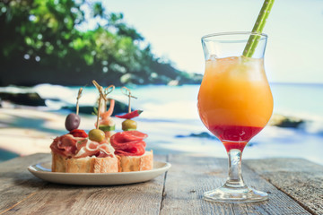 pineapple and orange cocktail with tapas on the beach