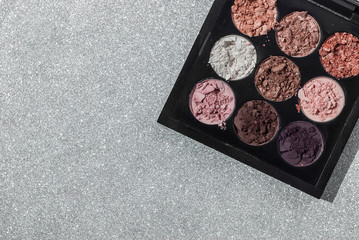 Crushed eyeshadow Cosmetic Powder on the silver glittery background. The concept of fashion and beauty industry. Abstract place for text texture mineral makeup