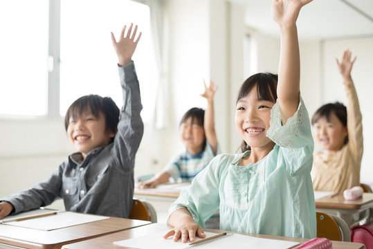 教室で手を挙げる小学生
