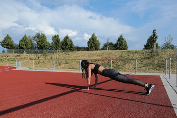Girl in sportswear performs sport exercises in the fresh air