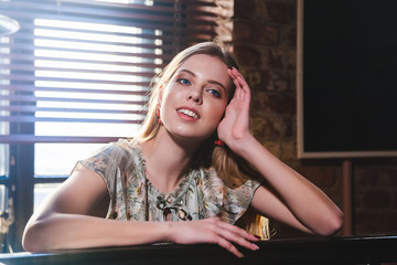 beautiful girl with natural blond hair and blue eyes is sitting at the bar counter and smiling