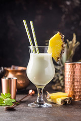 Homemade frozen Pina Colada cocktail with rum, coconut milk and pineapple garnish over black...