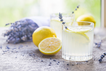 Lemonade with lemons and lavender on stone table over nature background
