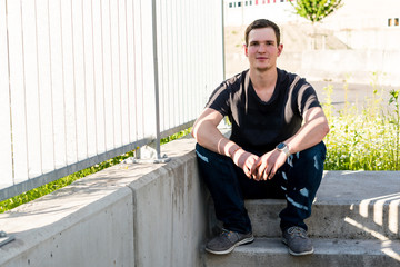 Junger Mann sitz auf Beton Treppe