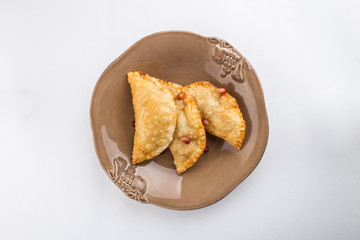 fried empanadas with pomegranate on brown plate isolated on white background