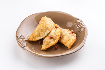 fried empanadas with pomegranate on brown plate isolated on white background