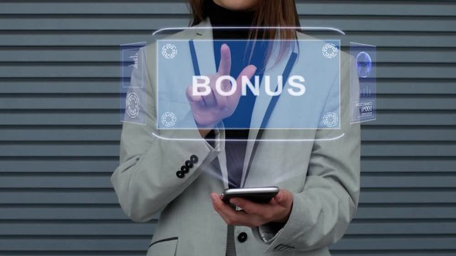 Unrecognizable business woman, interacts with a HUD hologram with text Bonus. Girl in a business suit uses the technology of the future mobile screen against the background of a striped wall