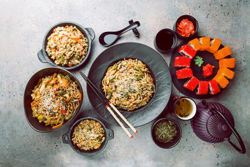 Asian food set served on gray stone background, top view. Chinese, japanese and vietnamese cuisine, sushi, rice and noodle.