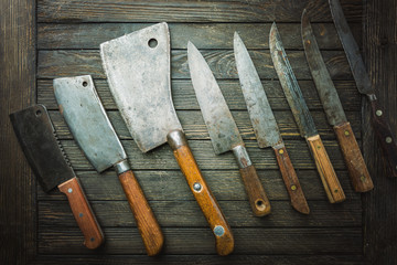 Set of Vintage kitchen knives and meat cleaver on dark wood background.