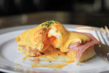 Egg Benedict with ham on white dish, English breakfast.