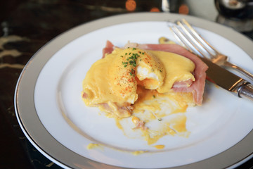 Egg Benedict with ham on white dish, English breakfast.
