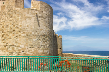 Brucoli castle detail of side tower with mount Etna far in the sea