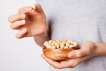 Obraz premium Woman's in hand hazelnut in a bowls. Healthy food and snack.