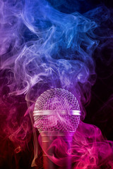 microphone enveloped in a colored cloud of smoke on black background.