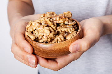 Woman's in hand walnut in a bowls. Healthy food and snack.