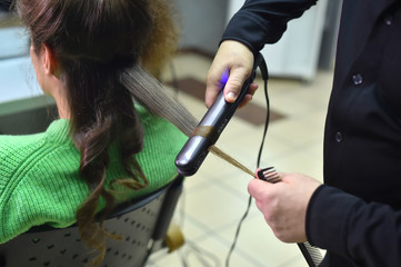 Woman hairdresser making hairstyle to girl in beauty salon