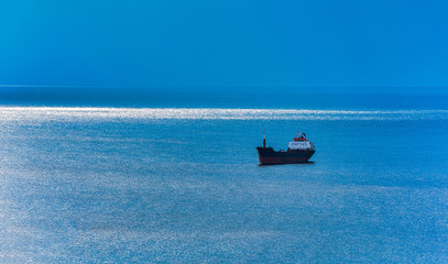 ship on the blue sea. a ray of sunshine close to the horizon line