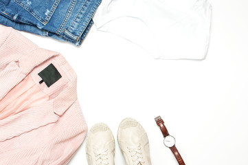 Stylish feminine spring clothing white shirt, blue jeans, pink corduroy jacket, beige espadrilles, watches on white background. Trendy hipster look. Female background blog concept Flat lay top view