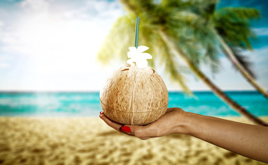 Fototapeta na wymiar Coconut in woman hand and beach background 