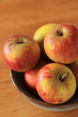 Composition with Yellow Red Apples in ceramic bowl top view vertical on wooden background.