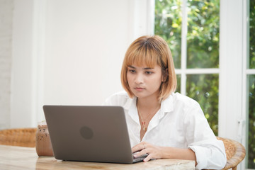 Asian businesswoman working on laptop in her workstation with tension. 