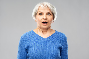 emotion, expression and old people concept - portrait of shocked senior woman in blue sweater with...