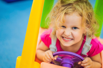 Little girl rides a toy colorful car