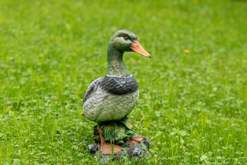 Obraz premium Close-up of a decorative figure of a duck on a background of green grass.