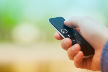 Hand holding remote control. Blured background. Remote control devices concept. Space for a text. Close up.