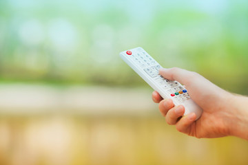 Hand holding remote control. Blured background. Remote control devices concept. Space for a text....