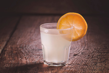 Lemon vodka on old dark wood table, dark toned image, selective focus