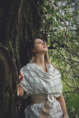 young woman in a checkered dressstay near a flowering tree