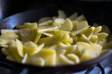 Raw potatoes are fried in a pan. The process of preparing fried potato