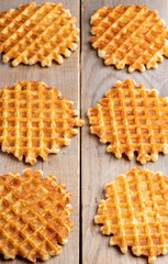 Six fresh baked round wafers on wooden table.