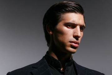 Obraz premium Closeup profile portrait of young man, isolated on a grey background, looking frowning a side. Horizontal indoors shot.