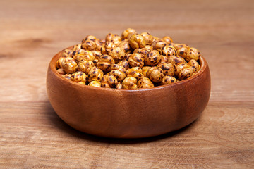 Roasted and dry chickpeas in a bowls on wooden table.