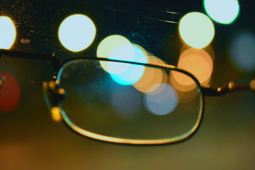 Night lights through glasses, bright spots on dark background,blur