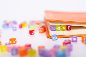 LOVE word on colorful bead block as bookmark in book. Love story fiction concept