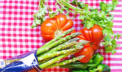 Tomate, espárragos verdes, pimientos y apio sobre mantel a cuadros 
