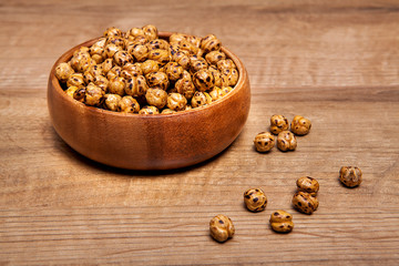 Roasted and dry chickpeas in a bowls on wooden table.