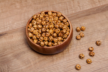 Roasted and dry chickpeas in a bowls on wooden table.