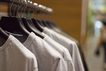 Grey t-shirts on hangers at clothing store , close up view