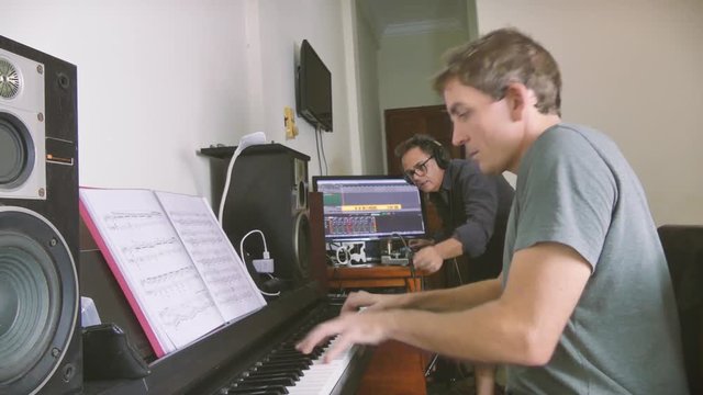 An indie musician singer-songwriter and a sound engineer audio mixing technician make a home recording using a DAW (digital audio workstation) with piano accompaniment.  Home and bedroom recording has