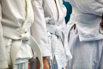 Concept karate, martial arts. Construction of students in the hall before training. Kimono, different belts, different levels of training. Close up,