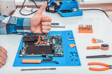 The repairman works in technical support, is engaged in the restoration and cleaning of the laptop.