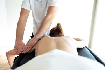 Young physiotherapist doing arms treatment to the patient in a physiotherapy room.