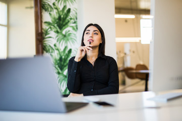 Beautiful business woman dreaming or thinking of new isea while working on computer at her office