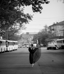 Ballerina standing in arabesque pose against the background of city street.